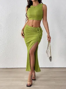 Detail of green ruched crop top and high slit skirt showing pleated fabric texture