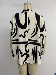 Dettaglio di blusa oversize con motivi geometrici neri astratti su tessuto bianco morbido