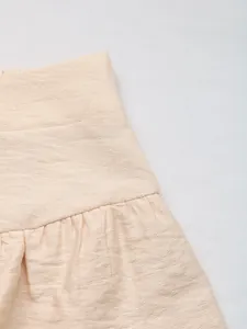 Detailed close-up of textured summer shorts featuring a wide waistband and pleated ruffles