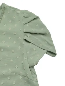 Detailed view of sage green Swiss dot fabric with elegant flutter sleeve design