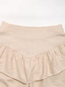 Detailed view of textured apricot fabric with layered ruffles and elastic waistband