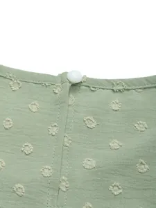 Detail of sage green jacquard fabric with dot texture and white button on the neckline