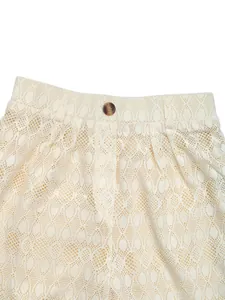 Détail d'un pantalon en dentelle taille haute avec bouton marron et maille fine