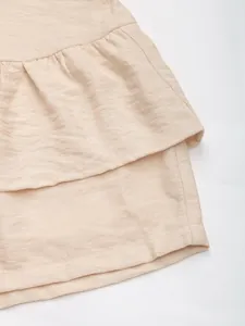 Close-up of layered ruffle details and textured fabric on beige summer casual shorts