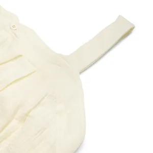 Close-up of baby romper showing textured cotton muslin fabric, buttons and shoulder straps