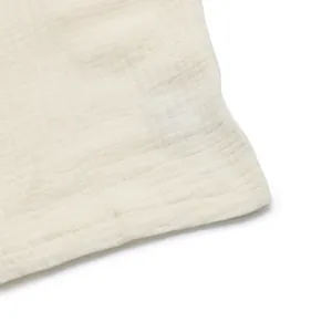 Detail shot of breathable beige textured cotton gauze fabric with neat stitching craft