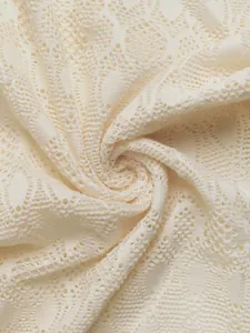 Détail macro du pantalon en dentelle montrant des motifs floraux et un tissu souple
