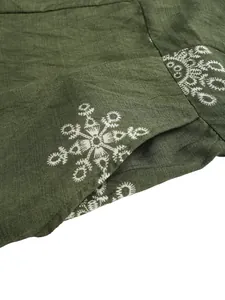 Detail of olive green linen fabric featuring delicate white ethnic embroidery patterns