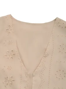 Détail du col en V et broderie anglaise beige aux motifs floraux sur le gilet d'été