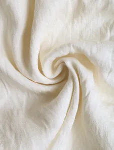 Dettaglio ravvicinato del tessuto bianco avorio con consistenza morbida e pieghe naturali