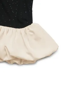 Détail du tricot noir scintillant avec un ourlet bouffant plissé de couleur crème