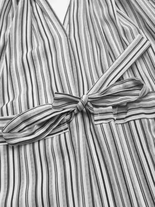 Détail du col en V et de la ceinture à nœud assortie sur la robe à rayures verticales