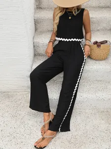 Détail du haut sans manches et pantalon large noir avec bordure ondulée blanche et couture