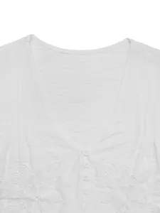 Detail of white V-neck blouse featuring pleated texture and delicate lace floral embroidery