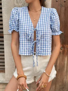 Détail du haut à carreaux bleus avec lacets, manches bouffantes et décolleté en V