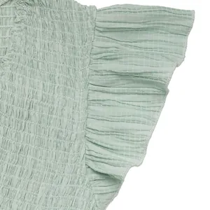 Détail du tissu vert clair texturé avec design froncé et ourlet de manche volanté
