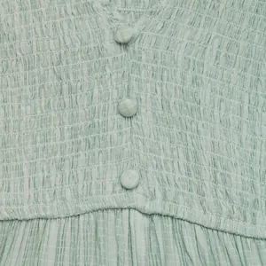 Détails du tissu vert clair avec texture froncée et boutons recouverts de tissu