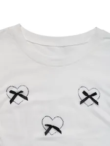Details von Strass-Herzen und schwarzen Schleifen auf einem weißen Rundhals-T-Shirt
