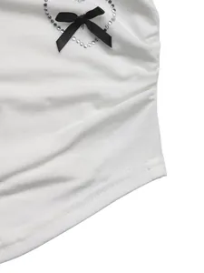 Detail eines weißen Slim-T-Shirts mit schwarzer Schleife und Strass-Herz-Verzierung