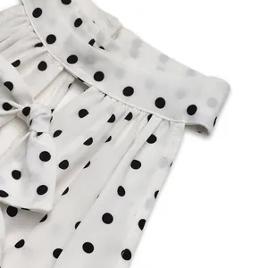 Detailed shot of white polka dot dress neckline featuring ruffled edges and ribbon tie-up