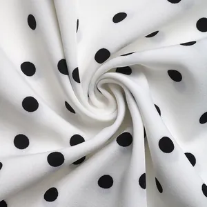 Close-up of white chiffon fabric with black polka dots showing soft texture and drape