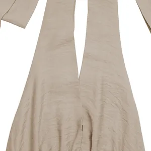Détail du tissu beige texturé avec plis élégants et bretelles croisées sur la pièce