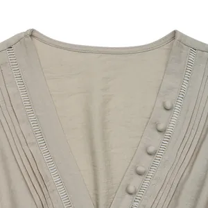 Detail of V-neck sleeveless top with decorative buttons and lace hollow stitching