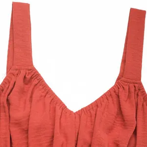 Détail macro de la robe rouge rouille avec décolleté en V et tissu plissé chic