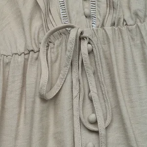 Detail of V-neck sleeveless dress with textured fabric, covered buttons and lace trim