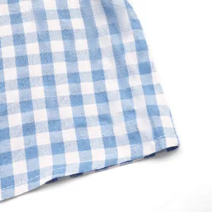 Détail de la texture du tissu vichy bleu et blanc avec couture précise sur l'ourlet
