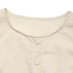 Detail view of sleeveless summer dress neckline with fabric-covered buttons and cotton texture