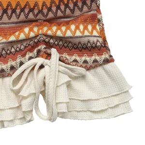 Detail of bohemian zigzag knit pattern with white tiered ruffles and drawstring closure