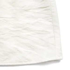Close-up of premium white cotton-linen fabric texture and neat hem stitching of the dress