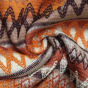 Macro detail of high-quality knit fabric with bohemian wavy patterns in orange and cream
