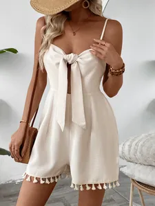 Close-up of cream waffle knit romper featuring delicate tassel fringe and bow tie details