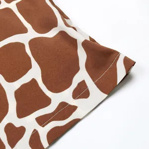 Detailed close-up of giraffe print fabric hem with precise stitching on summer shirt