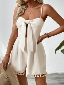 Detail of white waffle texture romper featuring delicate tassel fringe and bow tie design