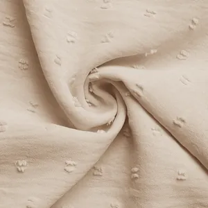 Macro detail of beige textured chiffon fabric with 3D dot embroidery and ruffles