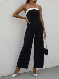 Detail of elegant black strapless jumpsuit featuring a white contrast trim and slim wide-leg cut