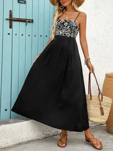 Detail of bohemian black maxi dress featuring white floral bodice and flowy long skirt