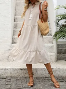 Dettaglio dell'abito beige senza maniche con scollo a V, nappe e gonna a balze
