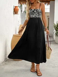Outdoor shot of a black sleeveless maxi dress with white floral embroidery and high waist