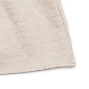 Dettaglio di abito beige senza maniche con tessuto a pieghe strutturato e cuciture piatte