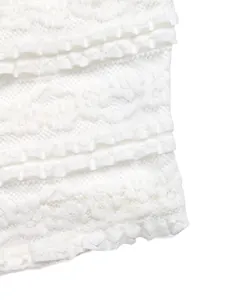 Vue macro du haut en dentelle blanche avec volants superposés et broderie détaillée