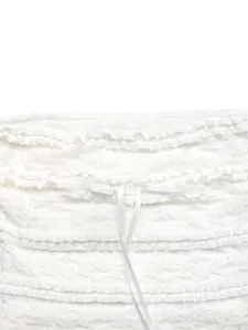 Détail de haut court en dentelle blanche avec volants multicouches et nœud en satin