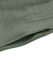 Close-up of pleated dark green fabric texture with precision sewing on the dress seam
