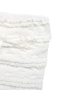 Détail de volants en dentelle blanche et nœud ruban sur un haut court tendance