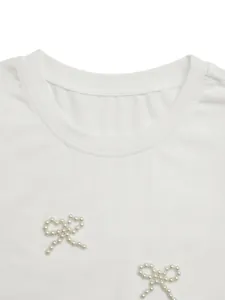 Close-up of elegant pearl bow embellishments on a premium white round neck T-shirt