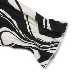 Detail of ruffled cuff with black and white abstract swirl print on a long sleeve dress