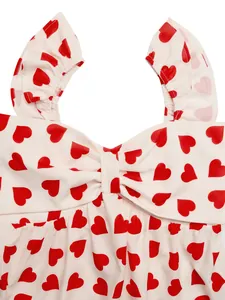 Macro detail of sweetheart neckline with bow and red heart prints on cream fabric